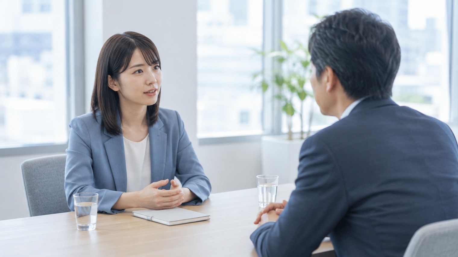 会議室で上司と向かい合って話をしている人のイメージ写真。